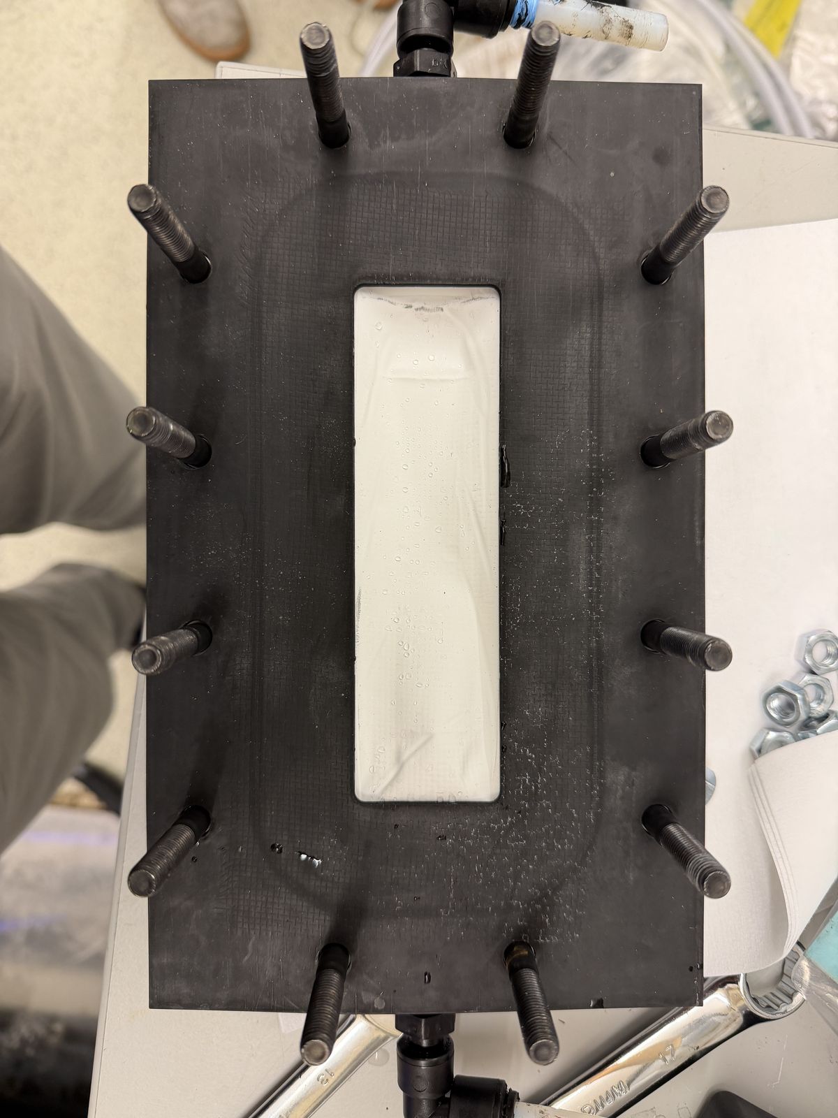 The gasket and housing stack partially assembled, condensation visible on the membrane surface before closing.