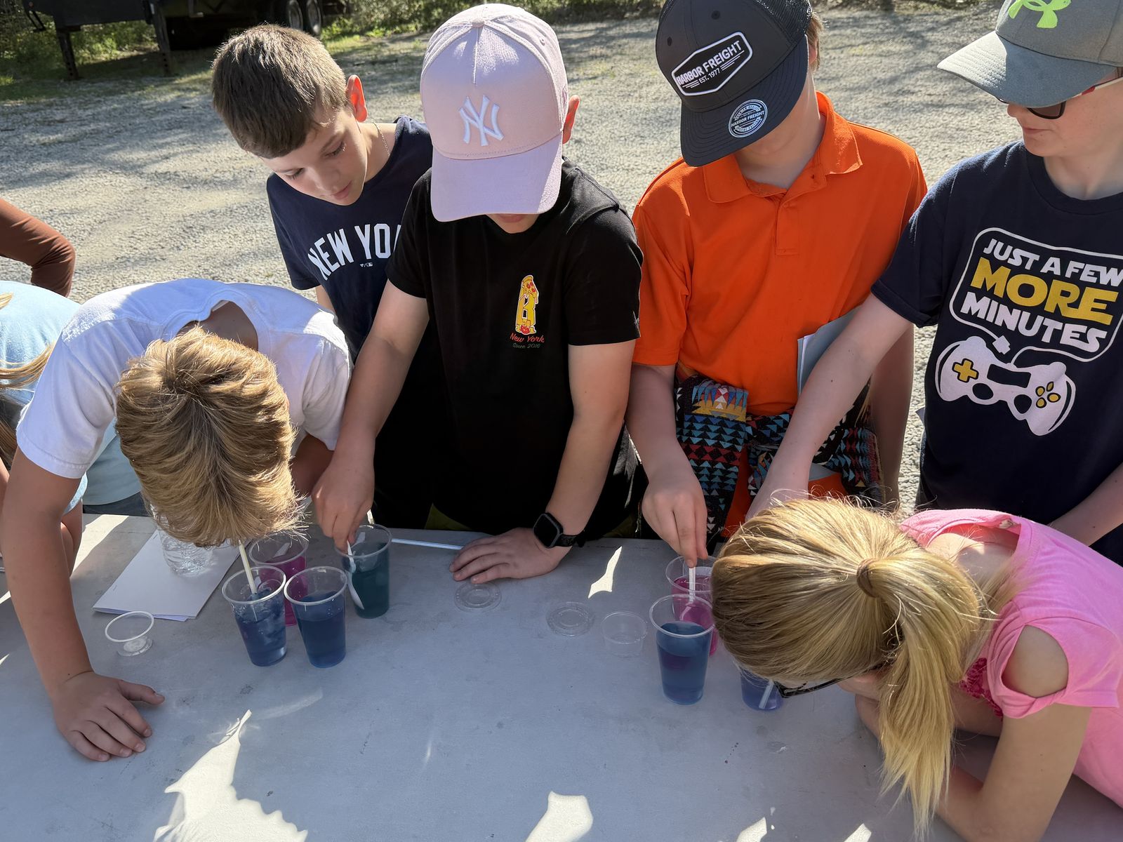 K-12 students outdoors running a hands-on water-testing demonstration at a ThermOcean outreach event.